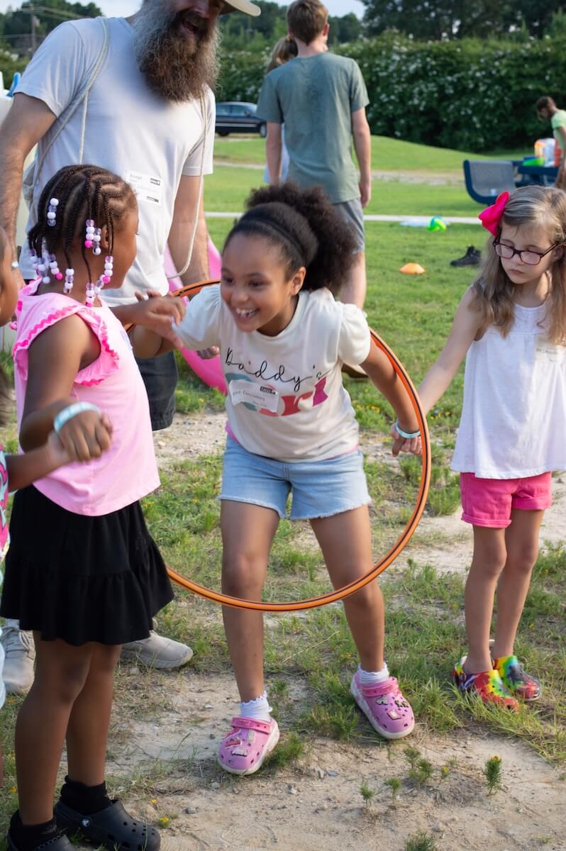 A camper laughing while playing with a hula hoop
